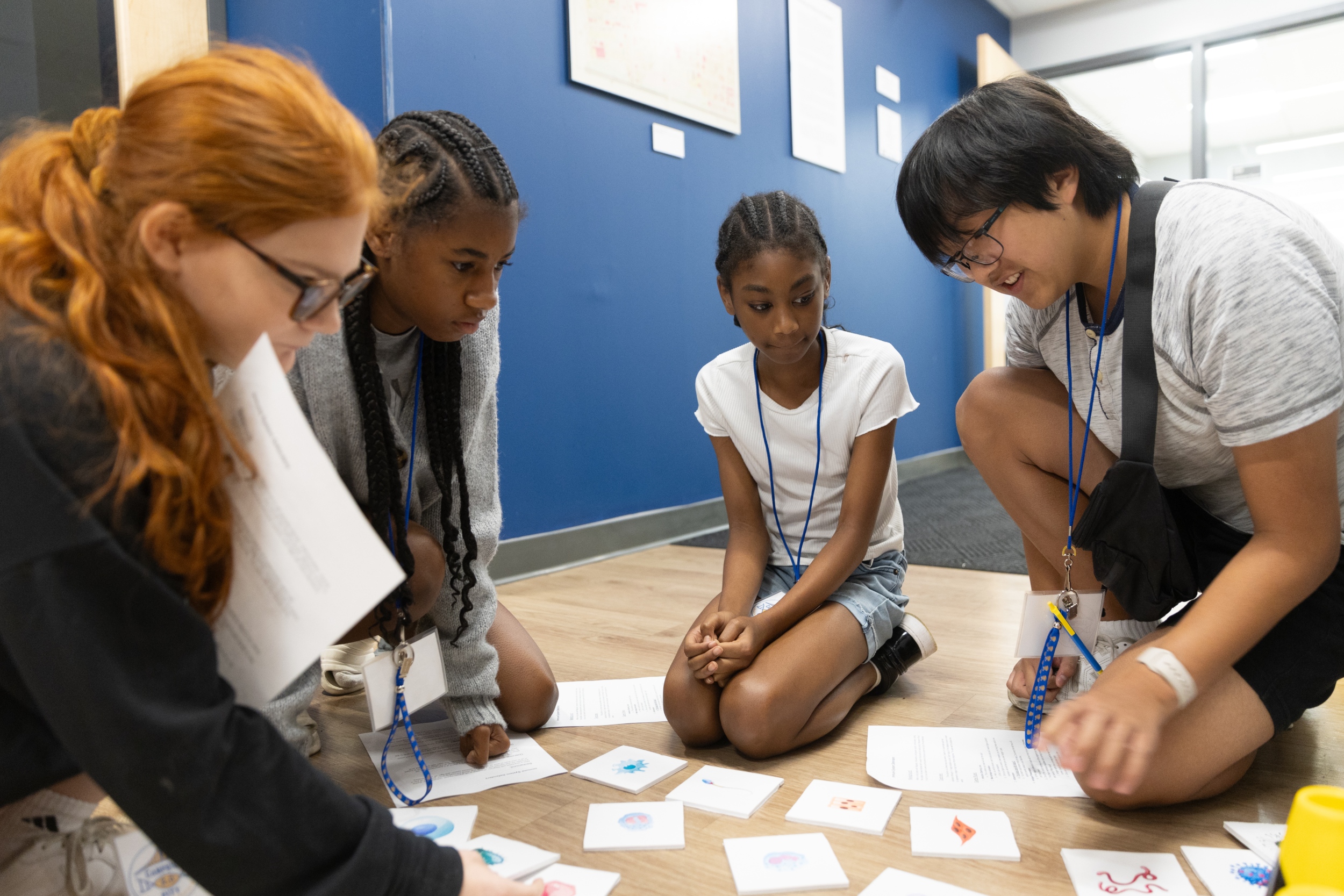 Camp BioE participants crouched on floor looking at different cards