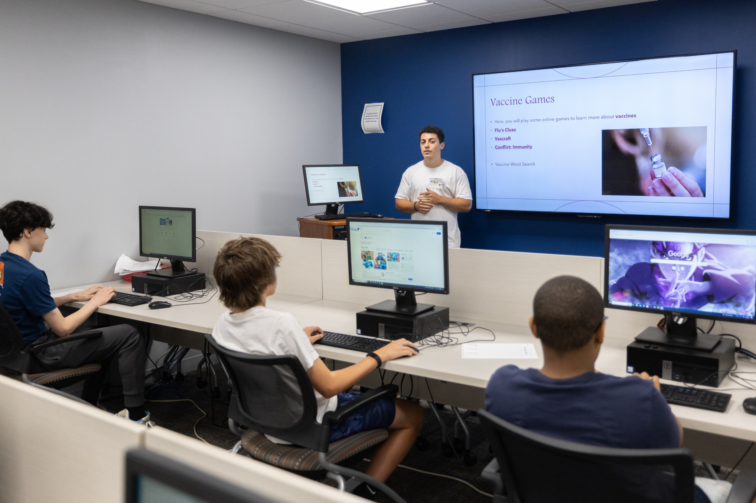 Three boys on desktop computers watching presentation